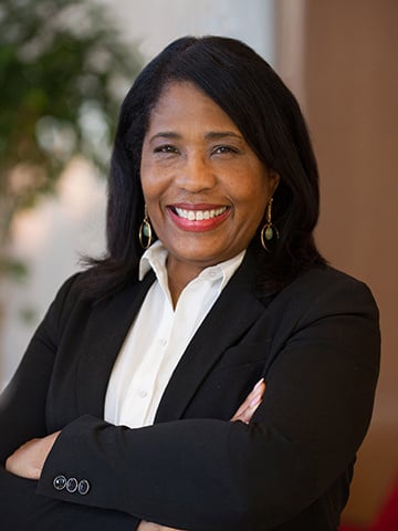 Pictured is Vice President of DICE, Rochelle D. Smith. A Black woman with shoulder length, straight hair and a wide, bright smile wearing a black suit jacket with white collared shirt.